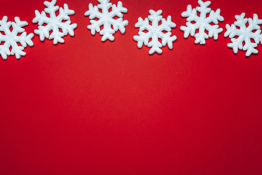 red background with white snowflakes and stars. place for text with christmas decorations