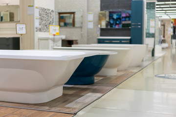 Fototapeta na wymiar White and blue bathtubs in a hardware store. The concept of choosing and installing bathtubs