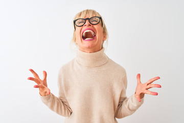 Middle age woman wearing turtleneck sweater and glasses over isolated white background crazy and...