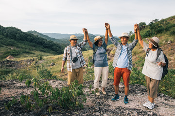 Group of elderly Asian lovers sit and relax on the foothills after they have climbed and adventure to this place. They use their free time after retirement. Mountain conqueror concept.