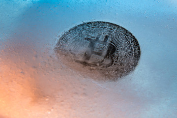 Silver Bitcoin, bit coin online digital currency frozen in the blue ice. Concept of block chain,...