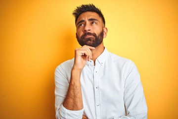 Indian businessman wearing white elegant shirt standing over isolated yellow background with hand...
