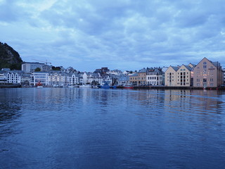 Scenic secessionist houses of european Alesund town reflected in water in Norway at blue hour