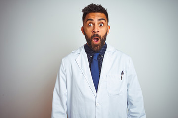 Young indian doctor man standing over isolated white background afraid and shocked with surprise expression, fear and excited face.