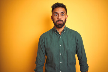 Young indian businessman wearing elegant shirt standing over isolated white background puffing cheeks with funny face. Mouth inflated with air, crazy expression.