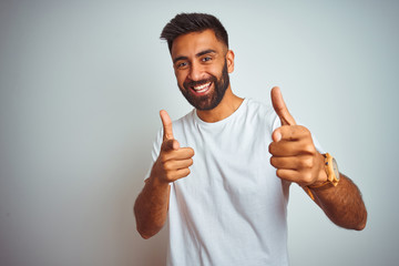 Young indian man wearing t-shirt standing over isolated white background pointing fingers to camera...