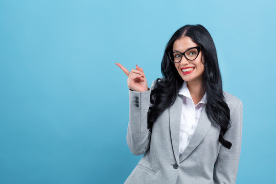 Young Woman Pointing At Something On A Blue Background