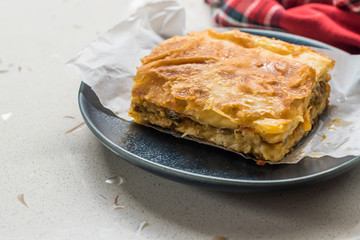Turkish Borek with Minced Meat and Leek on Wooden Board with Paper.