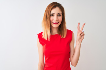 Redhead businesswoman wearing elegant red dress standing over isolated white background showing and pointing up with fingers number two while smiling confident and happy.
