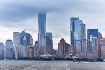 Obraz premium Cityscape of the financial district of Manhattan from Liberty Island, in a foggy day.