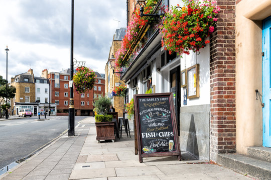 London, UK - September 14, 2018: Neighborhood of Westminster with nobody on pavement street by shops and placard sign for The Barley Mow cafe restaurant, flower decorations