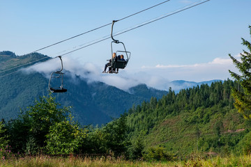 Tourists enjoy the mountain scenery from the transportation system chair lift in the Carpathian Mountains. Ukraine.