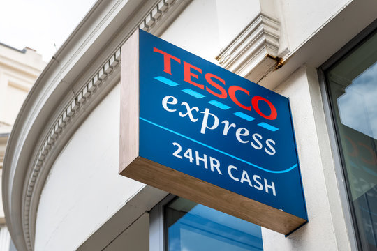 London, UK - September 16, 2018: Neighborhood Local Store Tesco Express Grocery Shopping Facade Exterior Entrance With Closeup Of Sign And 24 Hour Cash