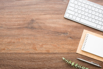 Wood office desk table with computer keyboard, notebook with pen. Top view with copy space, flat...