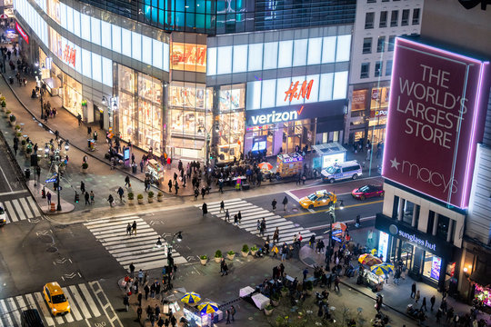New York City, USA - April 6, 2018: High angle view of H&M store at intersection of NYC Herald Square midtown with people crossing crosswalk and traffic cars at night
