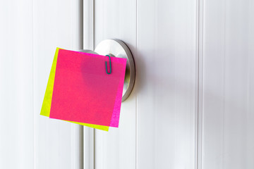 Abstract white door with metal doorknob is lock and sticker paper note on door. Text paper reminds the door for message.