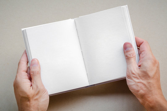Man hand holding blank opened book mock up with white pages. empty paper page for add textbook or template art work design note book.  - Powered by Adobe