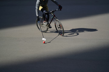 Fototapeta na wymiar Man plays urban bike polo. Cyclist hits the ball with a bundy, close up