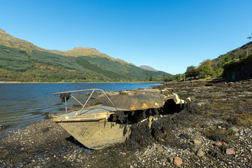 Fototapeta na wymiar Abandoned Fishing boat on loch long in the Trossachs National Park