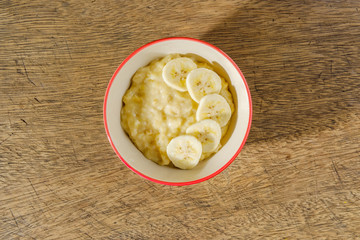 Mashed bananas in bowl on woodden backdrop