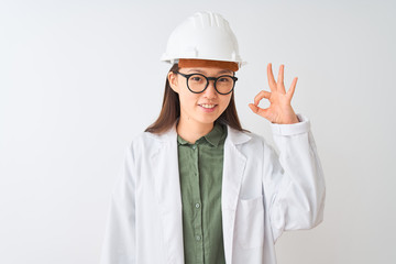 Young chinese engineer woman wearing coat helmet glasses over isolated white background smiling positive doing ok sign with hand and fingers. Successful expression.