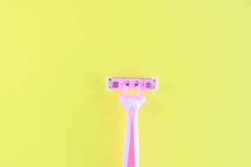 New pink disposable razor for safe shaving of female skin with selective focus on yellow background with copy space. Razor for smooth shaving. Sharp razors for personal hygienic routine