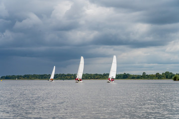 three sailing yachts against a stormy sky