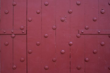 Close up of large old wooden red doors are beautifully decorated