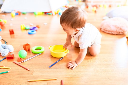 Adorable toddler crawling  around lots of toys at kindergarten