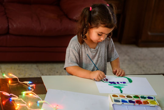 Portrait of cute little girl drawing at home with Christmas decorations.