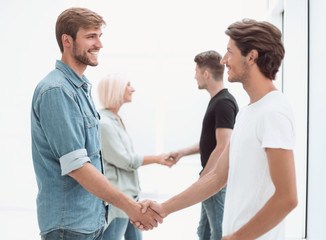 coworkers shaking hands in the office lobby.