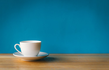 white cup of coffee on wooden table with blue background