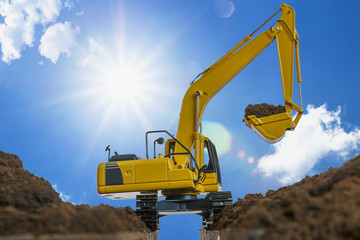 Yellow excavators are digging the soil in the construction site on the sky and sunlight background