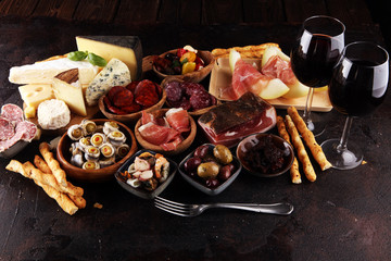 Italian antipasti wine snacks set. Cheese variety, Mediterranean olives, seafood salad, Prosciutto di Parma, tomatoes, anchovy and wine in glasses