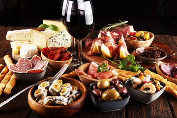 Italian antipasti wine snacks set. Cheese variety, Mediterranean olives, seafood salad, Prosciutto di Parma, tomatoes, anchovy and wine in glasses