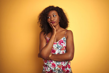 African american woman wearing floral summer t-shirt over isolated yellow background thinking looking tired and bored with depression problems with crossed arms.