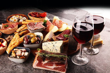Italian antipasti wine snacks set. Cheese variety, Mediterranean olives, seafood salad, Prosciutto di Parma, tomatoes, anchovy and wine in glasses
