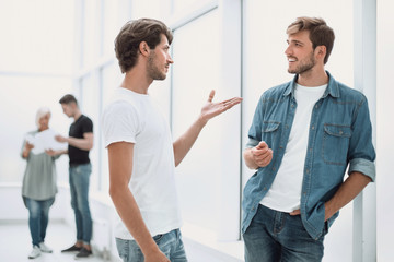 two colleagues talking standing in the office corridor