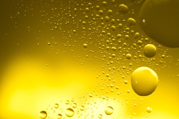 Yellow oil bubbles on water, cooking oil background.