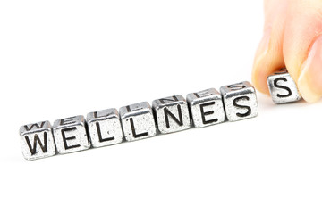 wellness concept with cube letters and a woman hand placing a letter