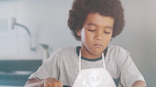 Young family cooking food in kitchen. Happy Little girl with her mother mixing batter. Mother and Little boy preparing the dough. Happy family in the kitchen and junior chef Concept. Cinematic 4k.