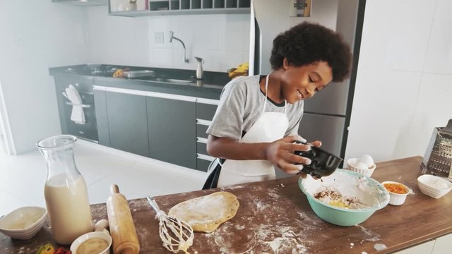 Young family cooking food in kitchen. Happy Little girl with her mother mixing batter. Mother and Little boy preparing the dough. Happy family in the kitchen and junior chef Concept. Cinematic 4k.