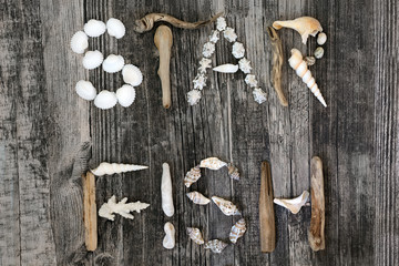 Abstract of driftwood, seashells & pebbles forming the word starfish on rustic wood background. Top view, flat lay.