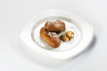 Riddled egg shaped sweet pastries in a white plate and on a white background.