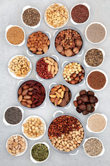 Dried nut and seed collection for vegans and vegetarians, health food high in antioxidants, protein, omega 3. minerals and vitamins. Flat lay on mottled grey background.