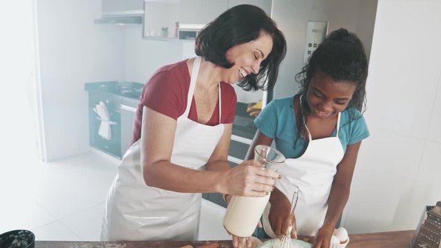 Young family cooking food in kitchen. Happy Little girl with her mother mixing batter. Mother and Little boy preparing the dough. Happy family in the kitchen and junior chef Concept. Cinematic 4k.