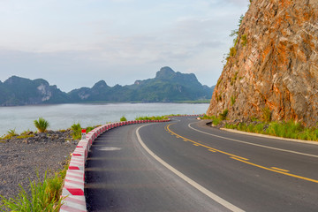 Winding asphalt road along the coast. Turning empty highway with sea and limestone mountains on background. Ha Long Bay, Vietnam.