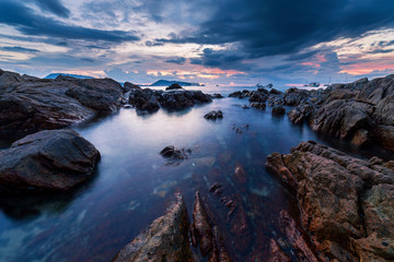 Long exposure image of Dramatic sky seascape with rock in sunset scenery background