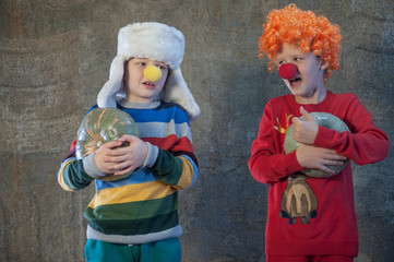 Two boys brothers in bright festive attire are holding pumpkins in their hands. Children dictate their message to Santa Claus before Christmas. Pupils sing songs and talk about successful studies