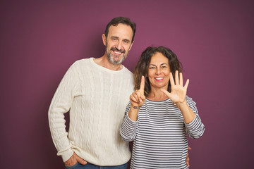 Beautiful middle age couple wearing winter sweater over isolated purple background showing and pointing up with fingers number six while smiling confident and happy.